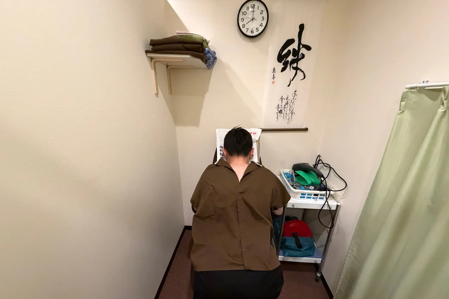 男性患者が背中が開く専用の施術着を着用し、施術椅子に座っている様子。